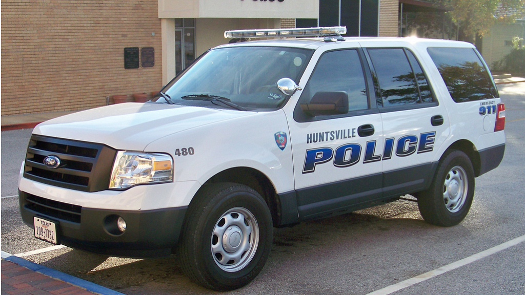 hunstville white police car with logo design parked beside building