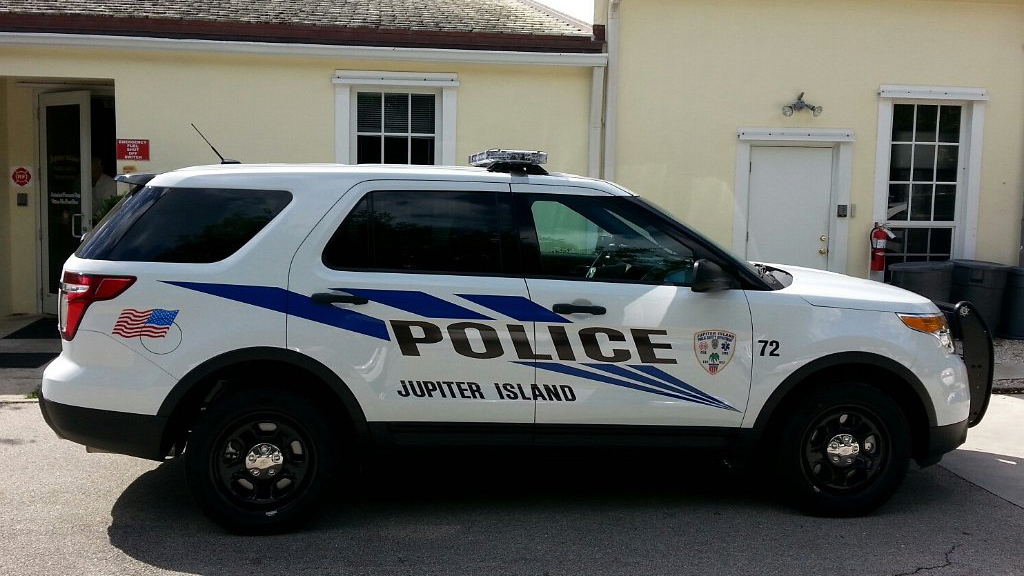 jupiter island white police car with blue line and logo design parked int the backyard